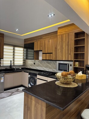 A modern kitchen with wooden cabinets, a central island, a built-in microwave, and a washing machine. - Warn and Cozy 2-bedroom apartment in perfect Dakar-Almadies (Dakar)