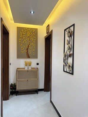 A hallway with a wooden cabinet, a wall-mounted flower art piece, and a ceiling light. - Warn and Cozy 2-bedroom apartment in perfect Dakar-Almadies (Dakar)