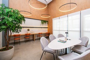 A modern meeting room with a white table, grey chairs, and a large potted plant. - Nex One Paraiso By Housi (São Paulo)