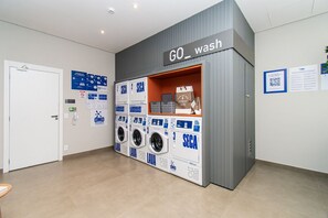 A public wash area with multiple washing machines and a sign that reads 'GO wash'. - Nex One Paraiso By Housi (São Paulo)