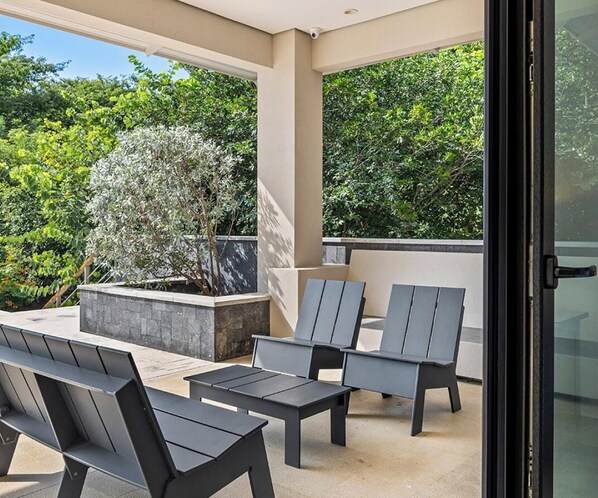 Eine Terrasse im Freien mit moderner Möbel, einem Steinpflanzgefäß und Blick auf üppiges Grün.