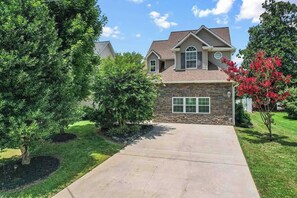 A residential house with a stone facade, a front yard with a tree, and a clear sky. - Lakefront w/ Private Dock / Pool Table +70" TV (Lexington)