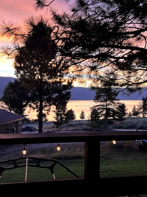 A view of a lake at sunset with trees in the foreground and a building in the background. - Spacious Lake House 5-bedrooms with Game Room in Cascade, ID (Cascade)