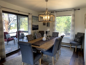 Un espace repas comprenant une table en bois, des chaises à revêtement gris et un lustre.