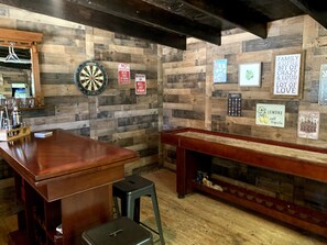 A bar area with wooden walls, a dartboard, a dartboard, a sign with a family quote, and a sign with a lemon quote. - Spacious Lake House 5-bedrooms with Game Room in Cascade, ID (Cascade)