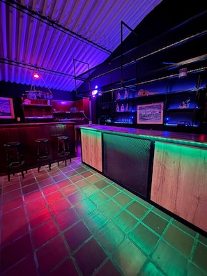 A bar area with stools, a bar counter, and shelves with bottles. - La Quinta Esperanza | Country house with a pool, sauna, and natural surroundings (La María)