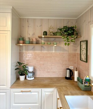A kitchen with wooden cabinets, a brick backsplash, and a coffee station. - Inviting, central apartment - Polaris (Tromsø)
