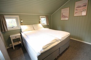 A bedroom with a single bed, two bedside tables, a window with curtains, and two framed pictures on the wall. - Inviting, central apartment - Polaris (Tromsø)