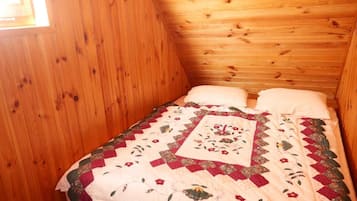 A small, cozy room with wooden walls and a single bed with a floral quilt.