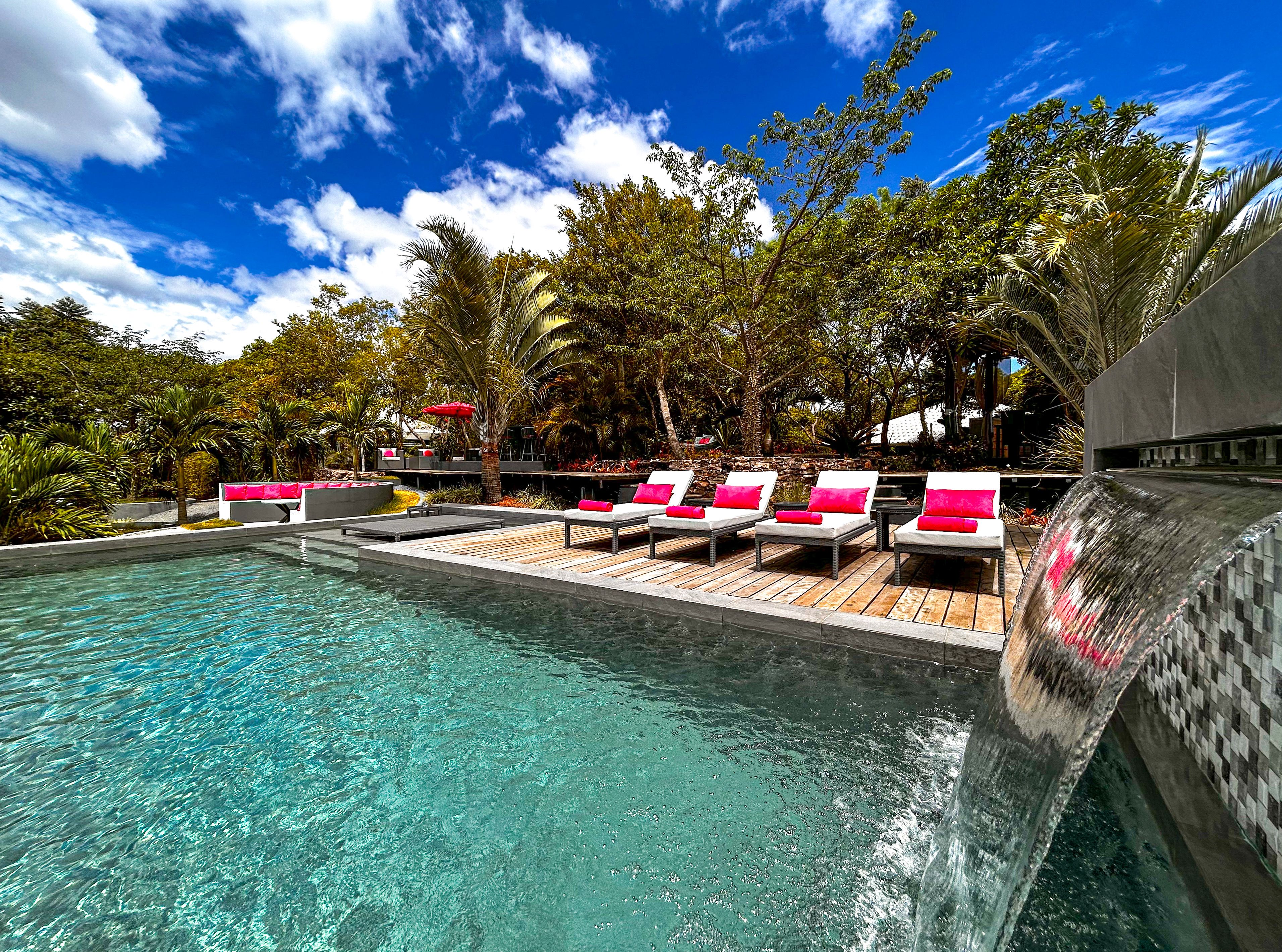 A pool area with lounge chairs and a waterfall feature.