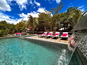 Zona de piscina con sillones de descanso y una cascada.