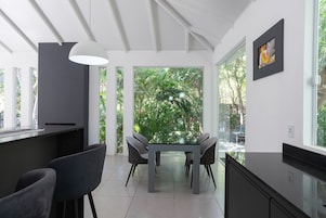 Una cocina moderna con comedor, ventanas amplias y vistas a zonas verdes.