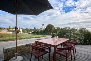 An outdoor patio with a table and chairs, a large umbrella, and a view of the surrounding area. - Morning Light | seeglueck (Reichenau)