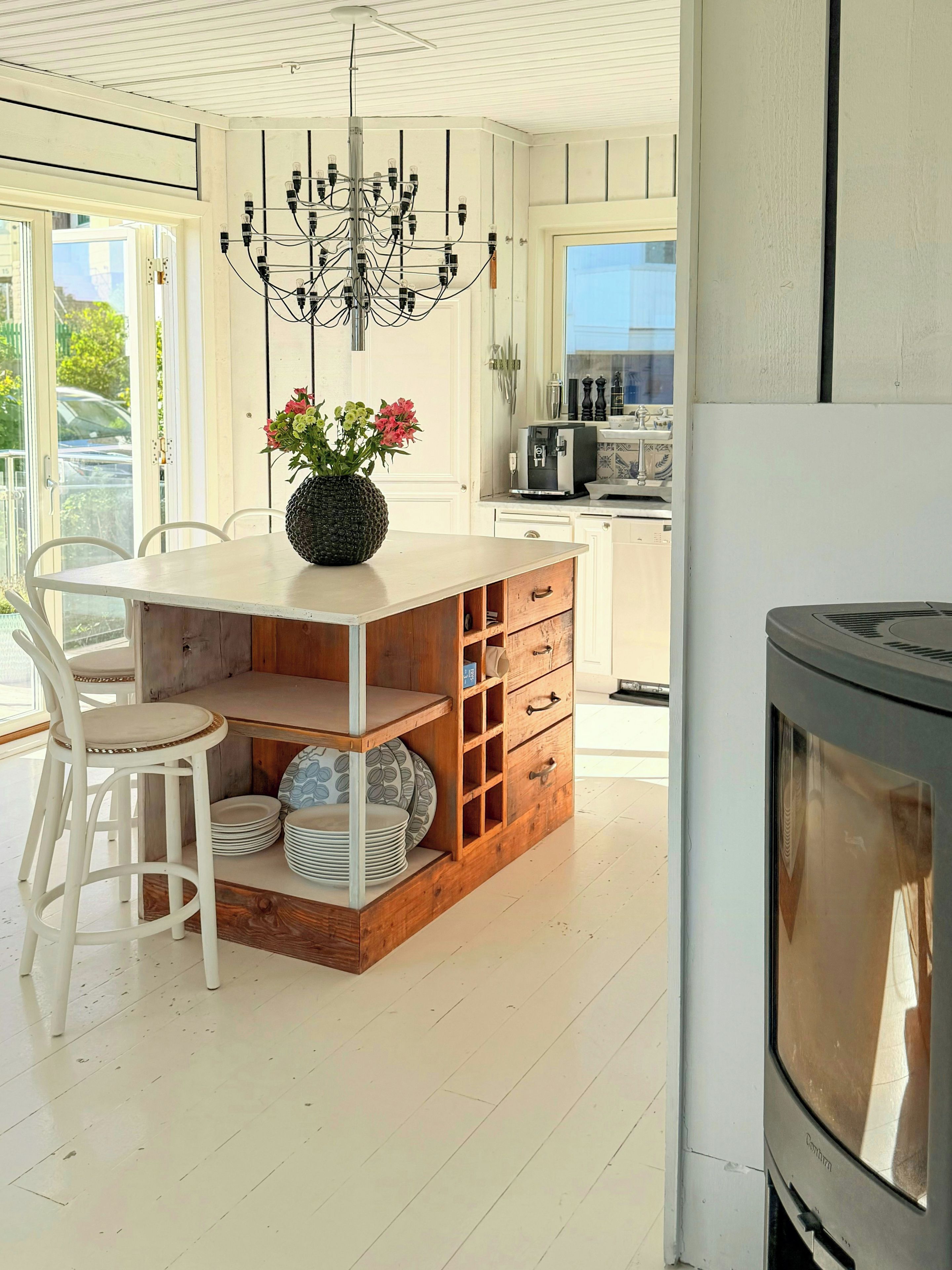 Een moderne keuken met een centraal eiland, witte kasten en een ingebouwde kookplaat.