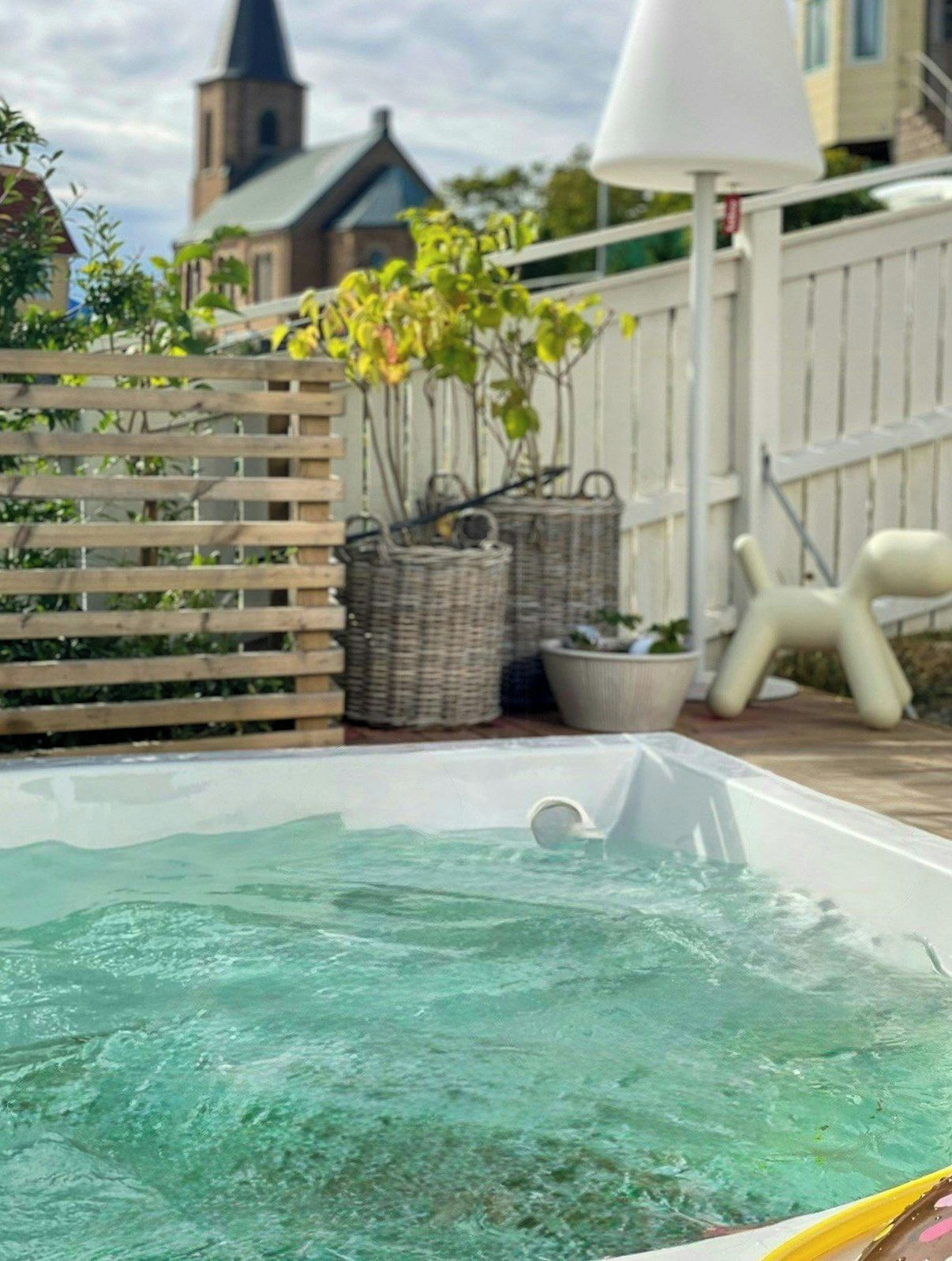 A hot tub with a wooden fence and wicker baskets in the background.