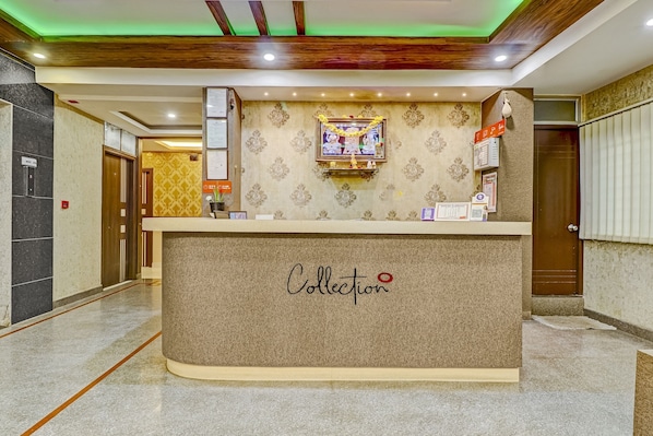 A reception desk with a 'Collection' sign, a framed picture above it, and a wall-mounted information board.