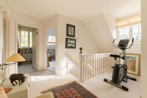 A spacious room with a ceiling fan, a treadmill, a small rug, and a staircase leading to another level. - Surrey Hills Family Home With Large Garden (Guildford)