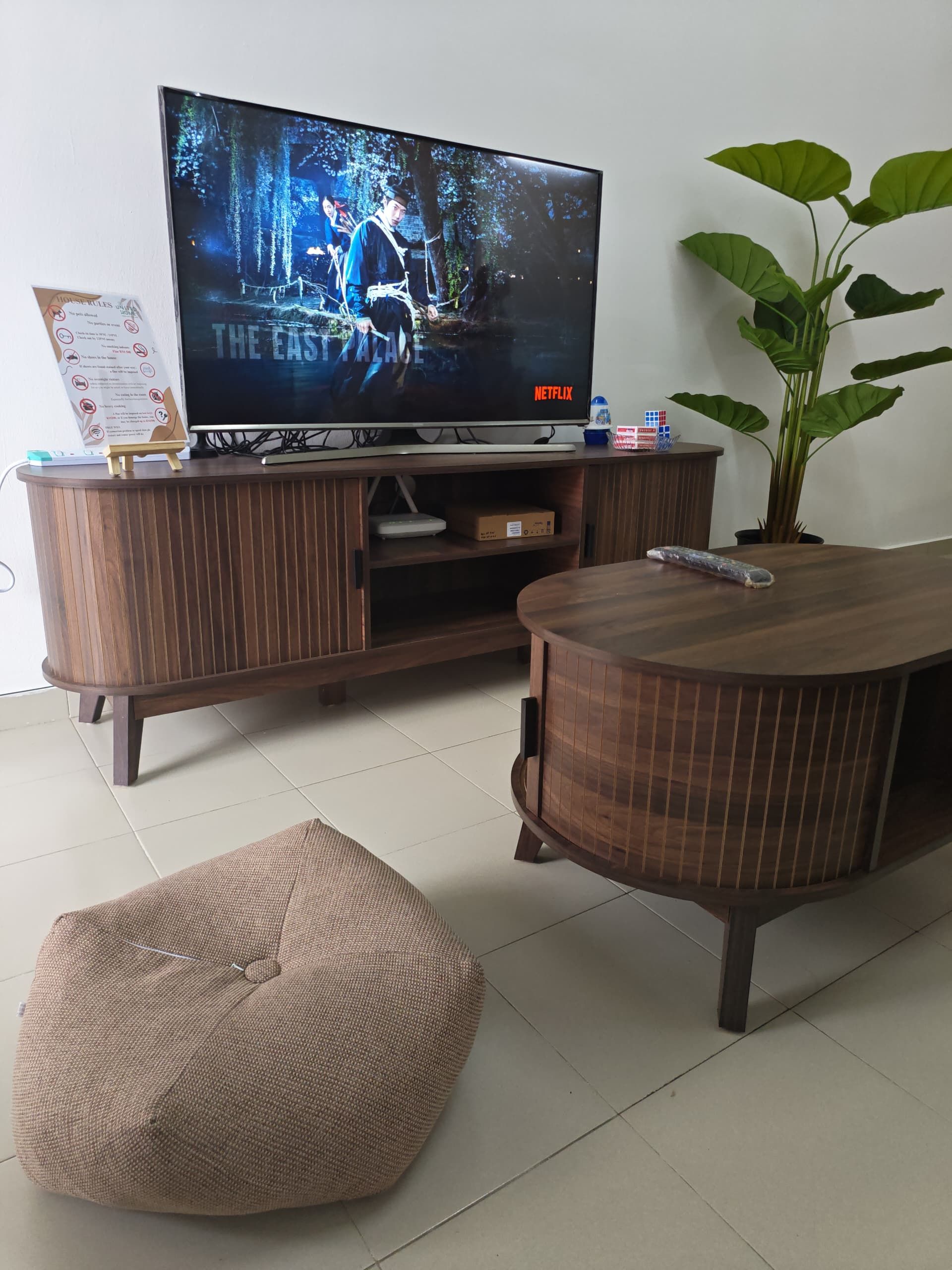 A living room with a television on a wooden stand, a bean bag chair, and a potted plant.