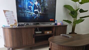 A living room with a television on a wooden stand, a bean bag chair, and a potted plant.