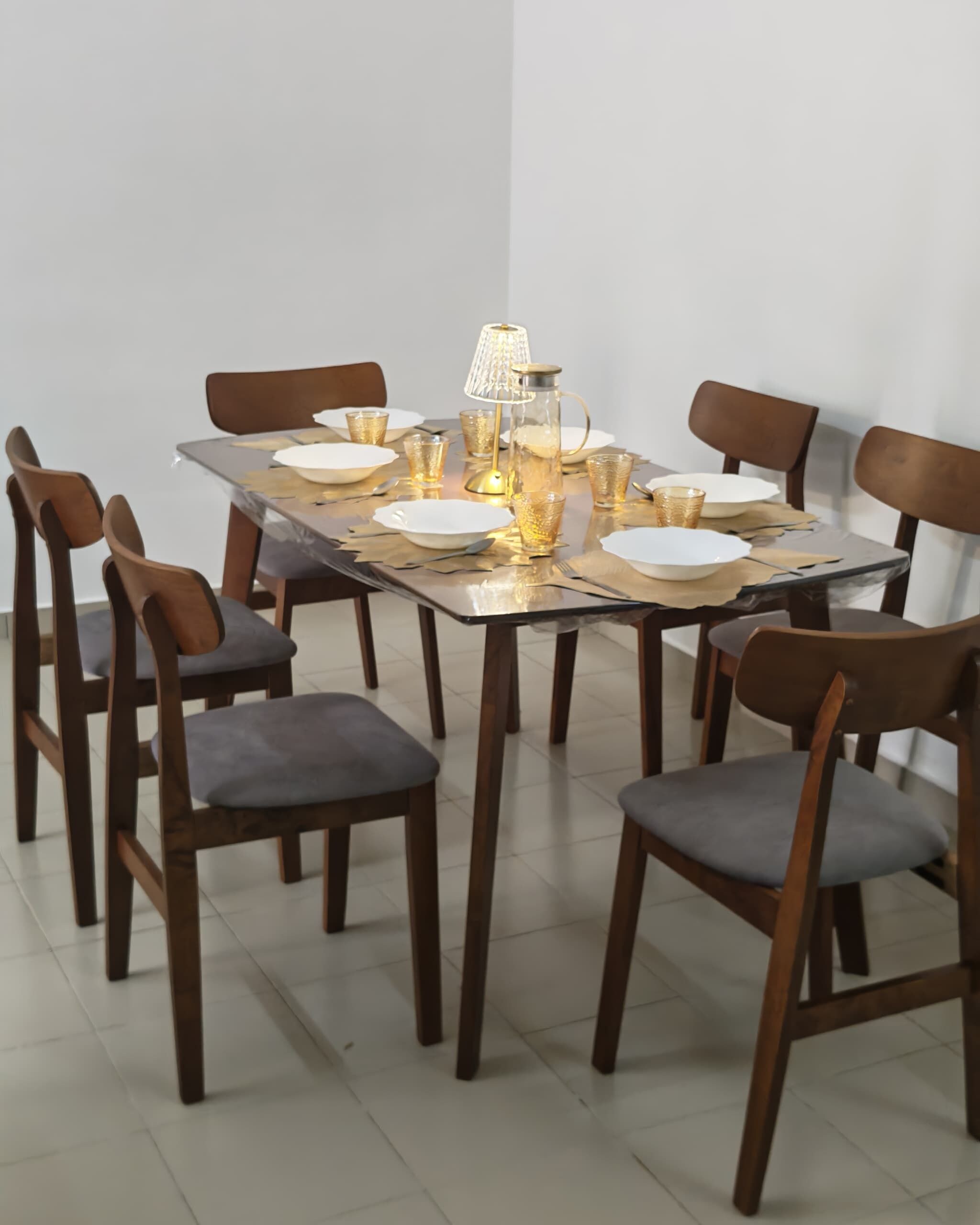 Una mesa de comedor dispuesta con platos, vasos y una lámpara.