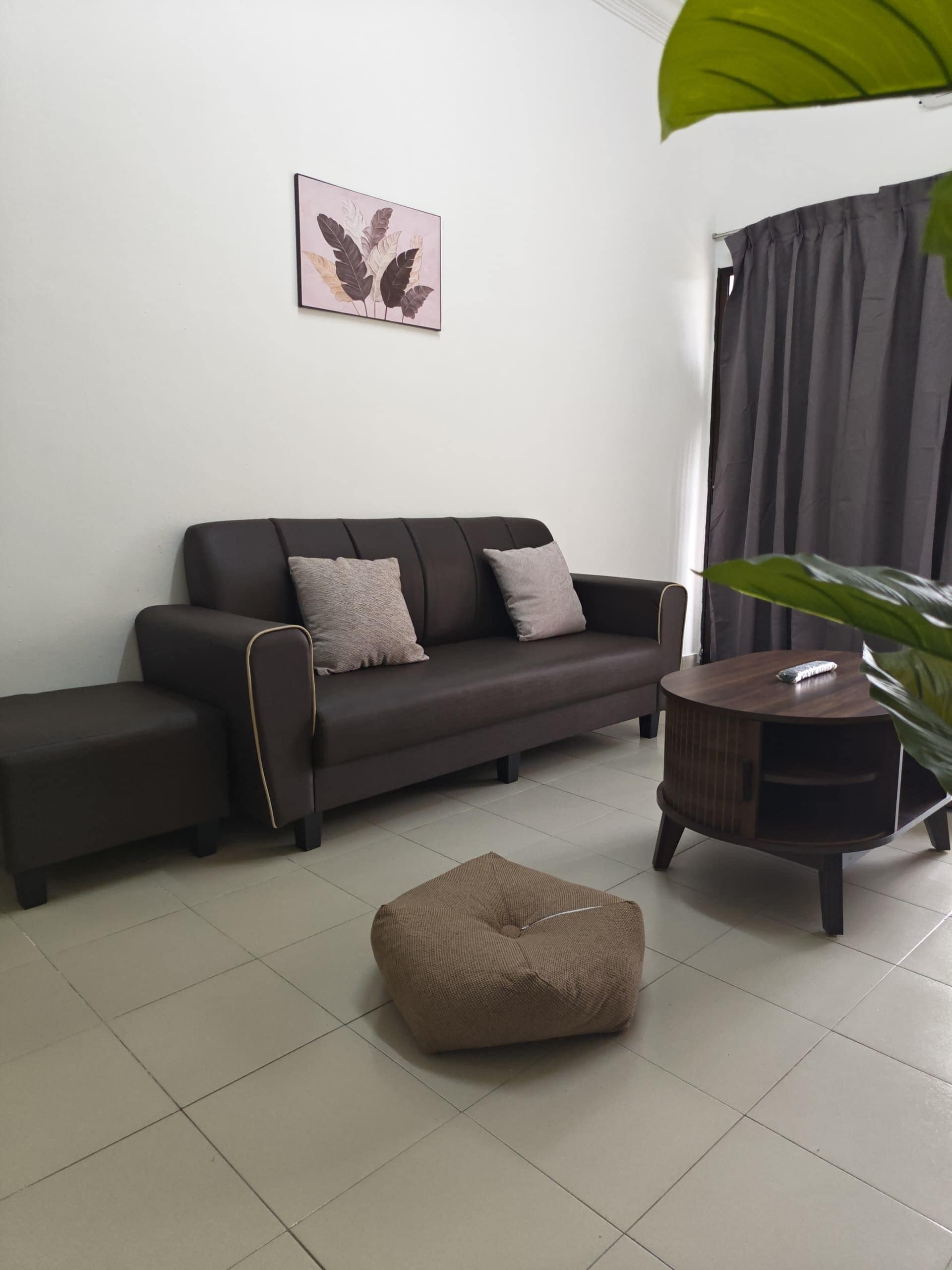 Una sala moderna con un sofá, un reposapiés y una mesita auxiliar.