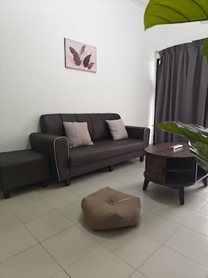 A modern living room with a sofa, ottoman, and a side table. - Palm Court Kuantan (Kuantan)