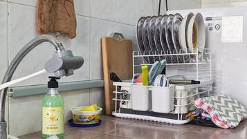Una cocina con un lavamanos, un escurreplatos y un adorno de osito de peluche.