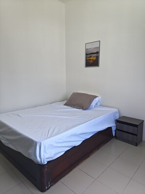 A single bed with a wooden frame, white bedding, and a small bedside table with a drawer. - Palm Court Kuantan (Kuantan)