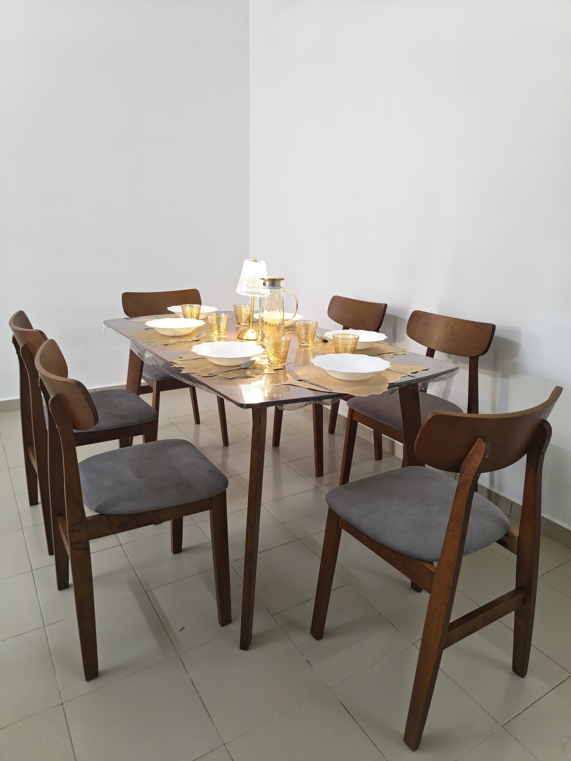 Una mesa de comedor con sillas, una lámpara y cristalería.