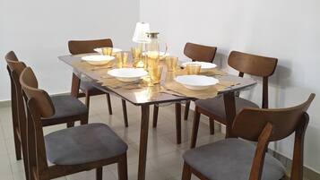 Una mesa de comedor con sillas, una lámpara y cristalería.