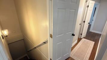 En trappa som leder till en dörr, en hall med en matta och en dörr med ett handtag.