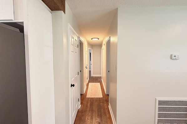 Un corridoio con pareti bianche, pavimento in legno e una lampada a soffitto.