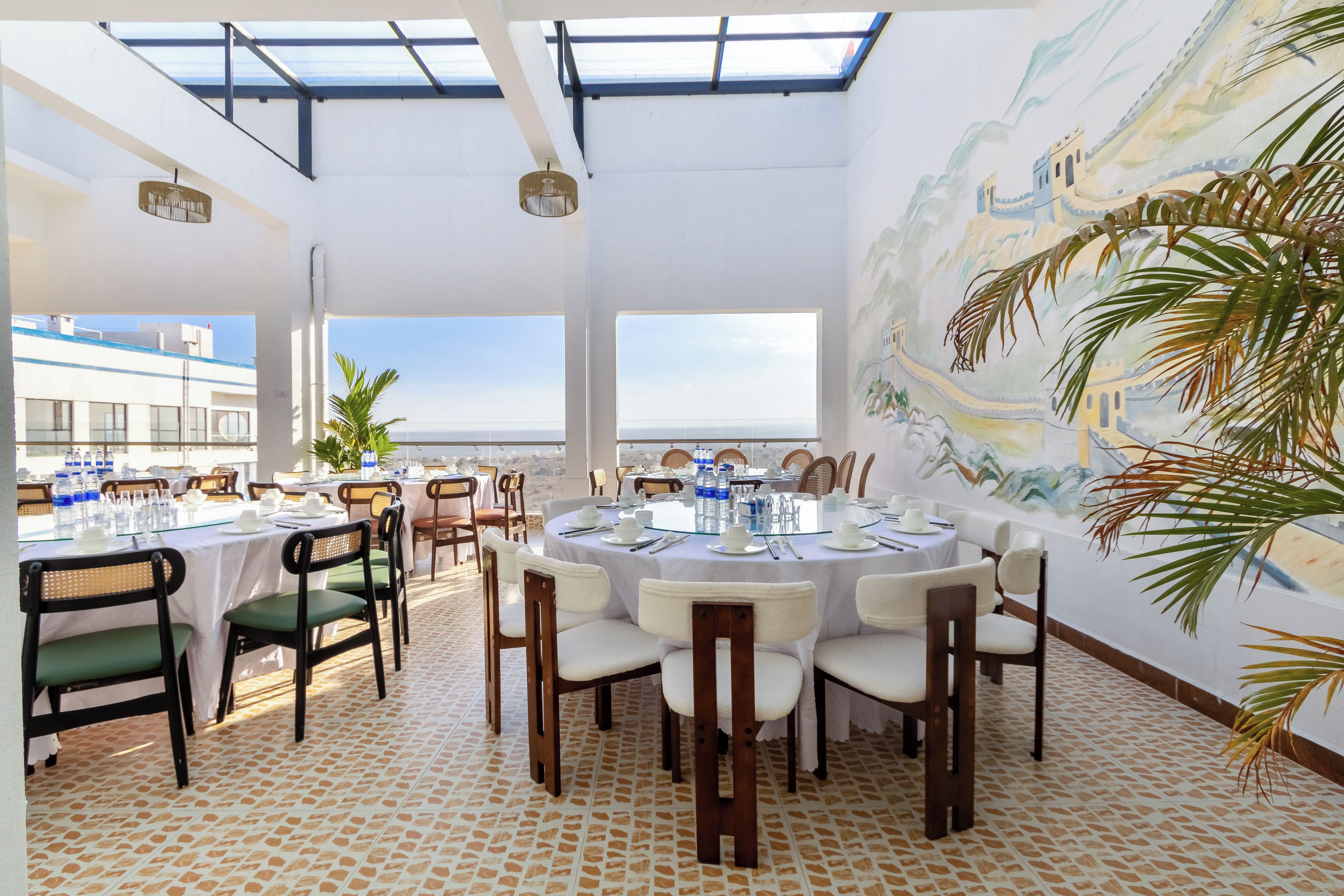 A dining area with round tables, chairs, and a mural on the wall.