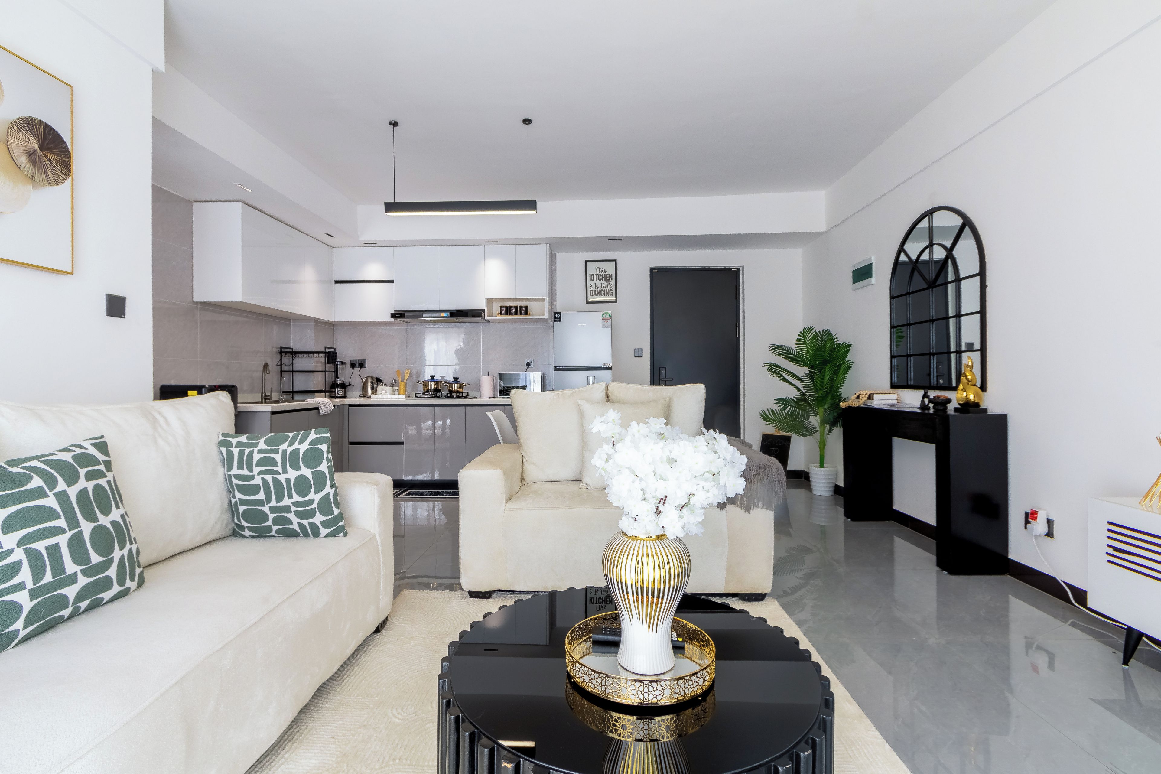 Una sala de estar moderna con sofá, mesa de centro y una cocina al fondo.