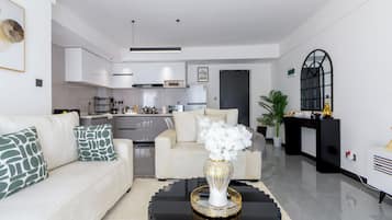 Una sala de estar moderna con sofá, mesa de centro y una cocina al fondo.