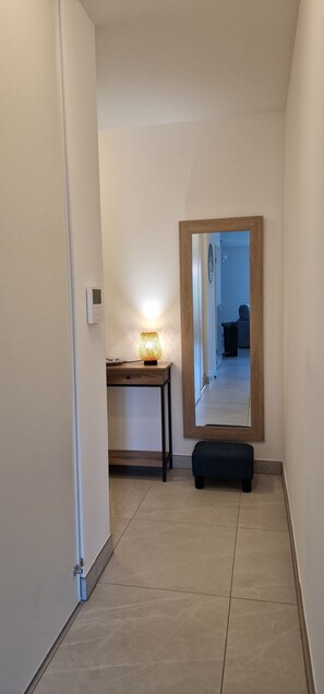 A hallway with a wooden table, a floor lamp, and a mirror on the wall. - Le Cocon Océan – 3-Bedroom Vacation Rental with a Terrace in Moliets (Moliets-et-Maa)
