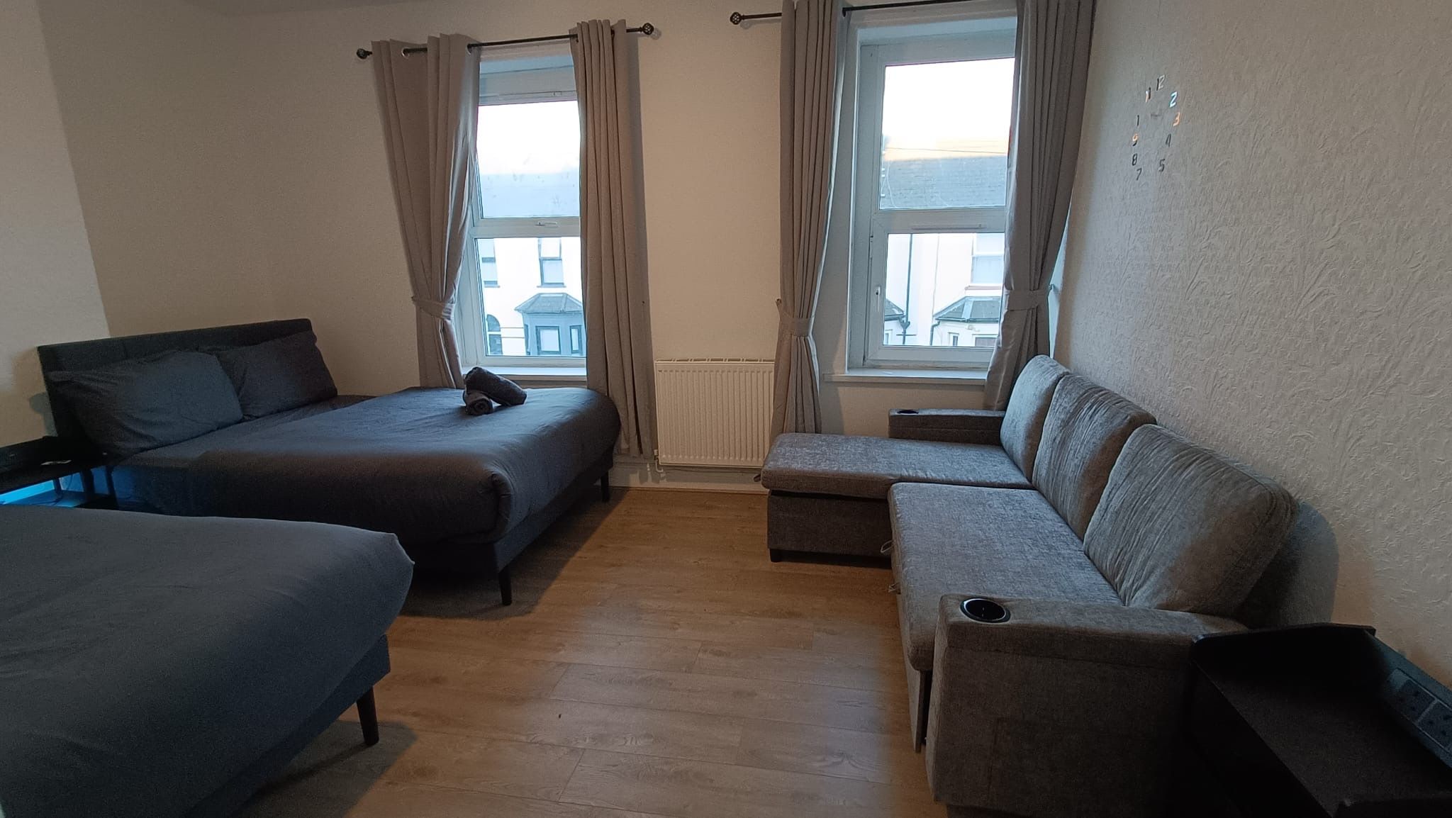 A hotel room with two beds, a sofa, and a window with curtains.