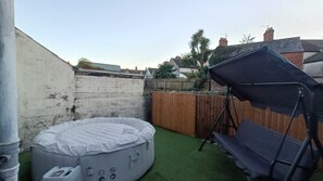 Un pati amb una banyera d'hidromassatge, un balancí i una tenda.