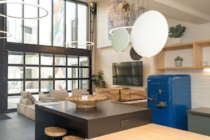 Eine moderne Küche mit einem blauen Kühlschrank, einer großen Kochinsel mit Barhocker und einem Essbereich mit einer Couch und Stühlen.