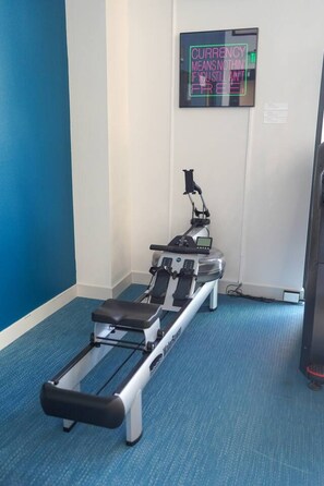 A medical examination table with a monitor in a room with blue walls and carpet. - Vibrant Japantown Townhome | Walk to Dining (San Jose)