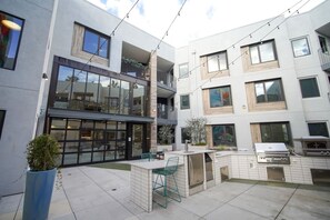 A modern apartment complex with a patio area featuring outdoor furniture and a barbecue grill. - Modern J-Town Townhome | Bright & Stylish (San Jose)