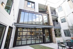 A modern building with large glass windows, a flat roof, and a balcony with metal railings. - Modern J-Town Townhome | Bright & Stylish (San Jose)