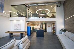 A spacious living area with a high ceiling, a dining table, sofas, and a kitchen in the background. - Modern J-Town Townhome | Bright & Stylish (San Jose)