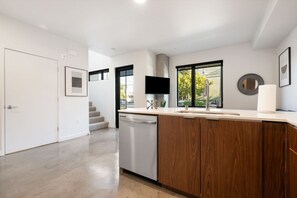 Una cocina moderna con lavavajillas, armarios de madera, un lavabo y una ventana que ofrece vistas al exterior.