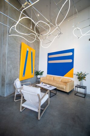 Un interior moderno con un sofá, sillas y arte abstracto en las paredes.
