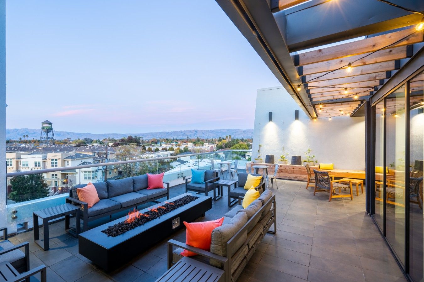 Una terraza en la azotea con mobiliario exterior, una chimenea y vistas de la ciudad.