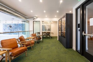 A modern interior with leather seating, a green carpet, and a view of the street through glass doors. - Silicon Valley Basecamp | Townhome in Japantown SJ (San Jose)