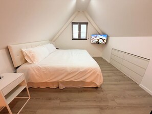 A bedroom with a bed, a TV mounted on the wall, and a window with blinds. - Modern Downtown Loft Walk2Beach I CasaAmarilla304 (Oranjestad)