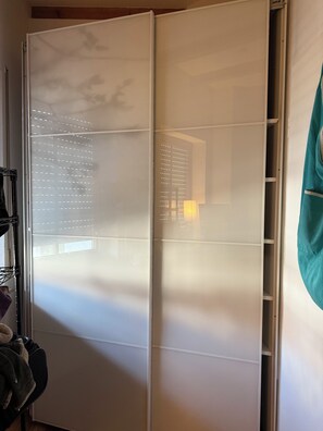 A room with a sliding door, a shelf unit, and a hanging garment rack.