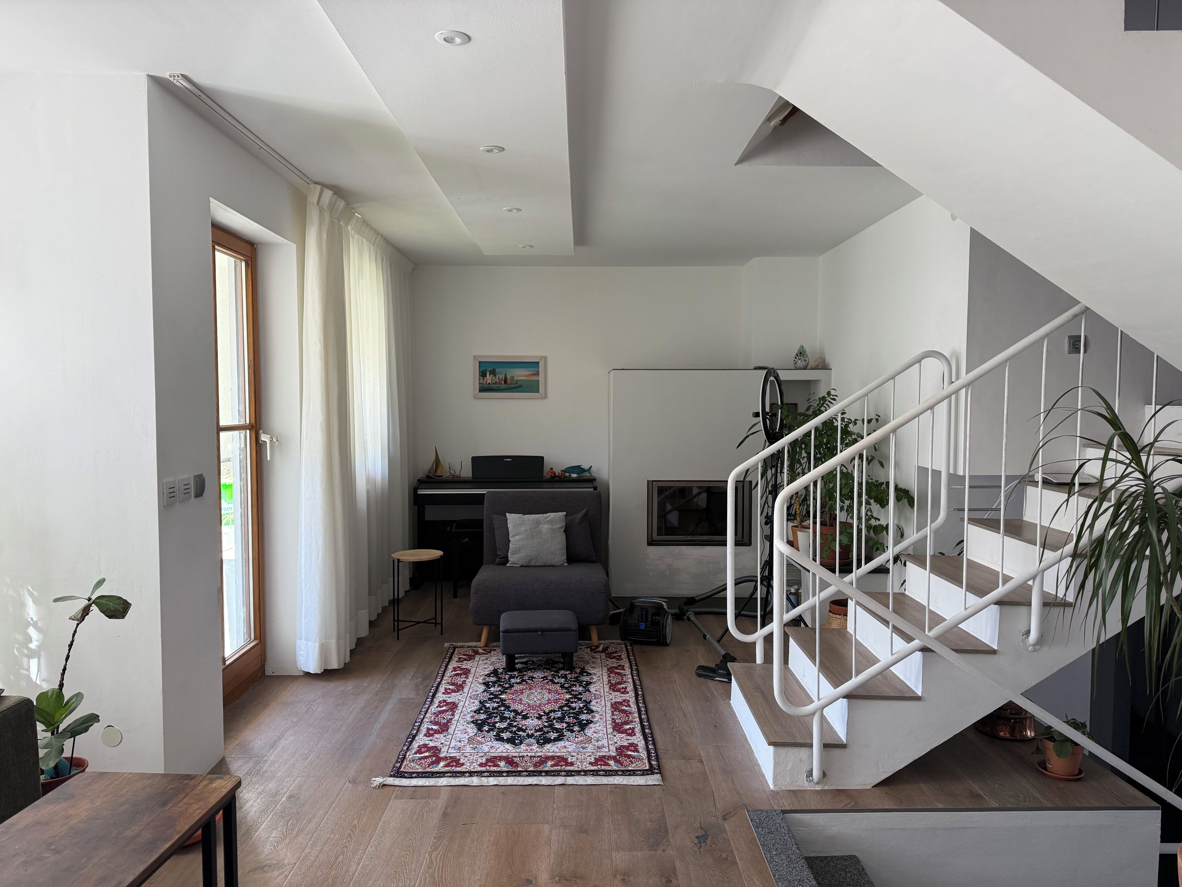 Ein modernes Wohnzimmer mit einer Couch, einem Schreibtisch, einer Treppe und einer Zimmerpflanze.